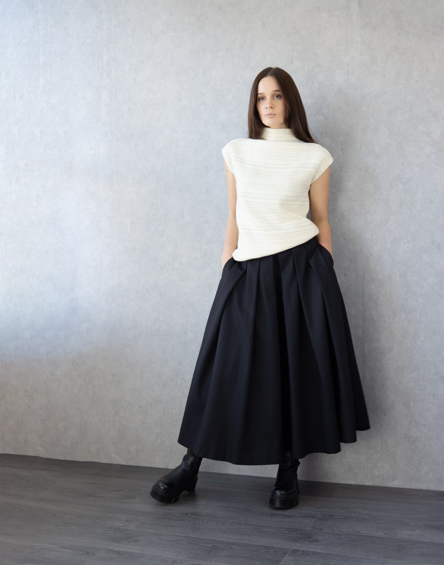 Black cotton skirt pants showing pleated volume and high waist silhouette
