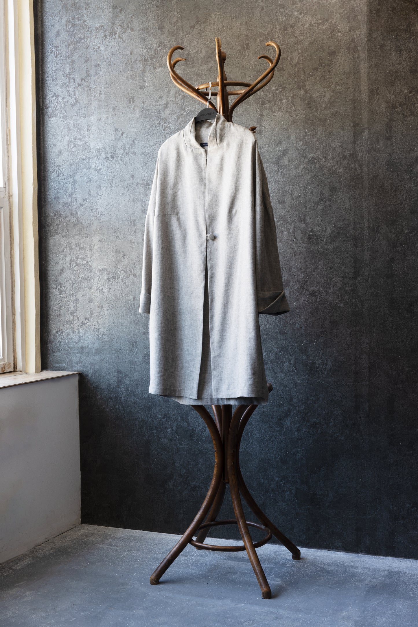 Front view of the lightweight linen coat on a hanger – minimalist silhouette