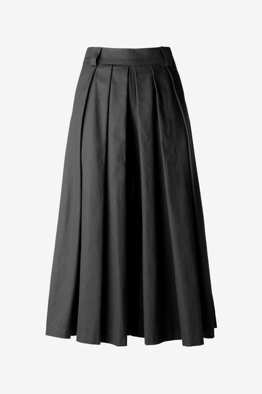 Front view of black sculptural skirt pants with pleats, worn as wide-leg trousers
